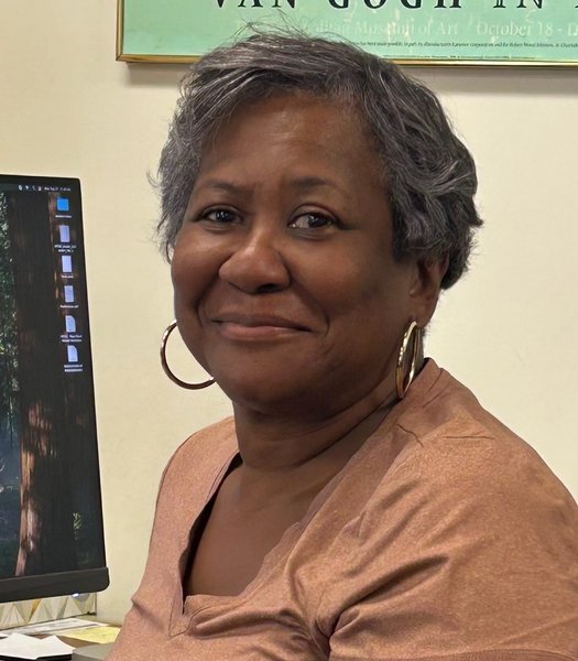 Headshot of Natalie Williams smiling with a computer monitor off to her side.